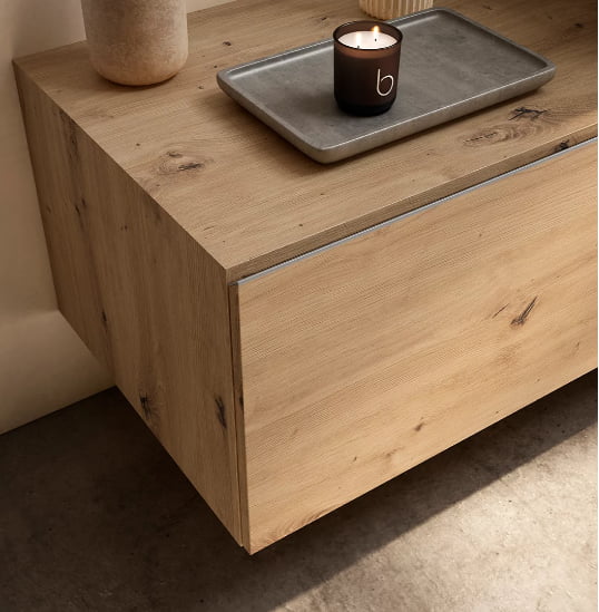 Zoom sur un meuble de salle de bain suspendu en bois clair avec rangements.