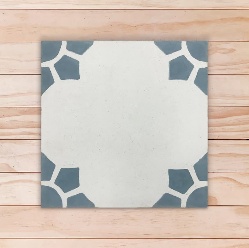 Carreau de ciment floral gris avec motifs bleu gris dans les coins formant un soleil ou une fleur
