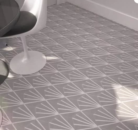 Carreau de ciment hexagonal à fond gris avec des traits blancs partant d’un même point, posé au sol