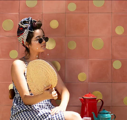 Carreau de ciment Dots laitonné posé au mur sur fond terracotta avec ronds en laiton de différentes tailles